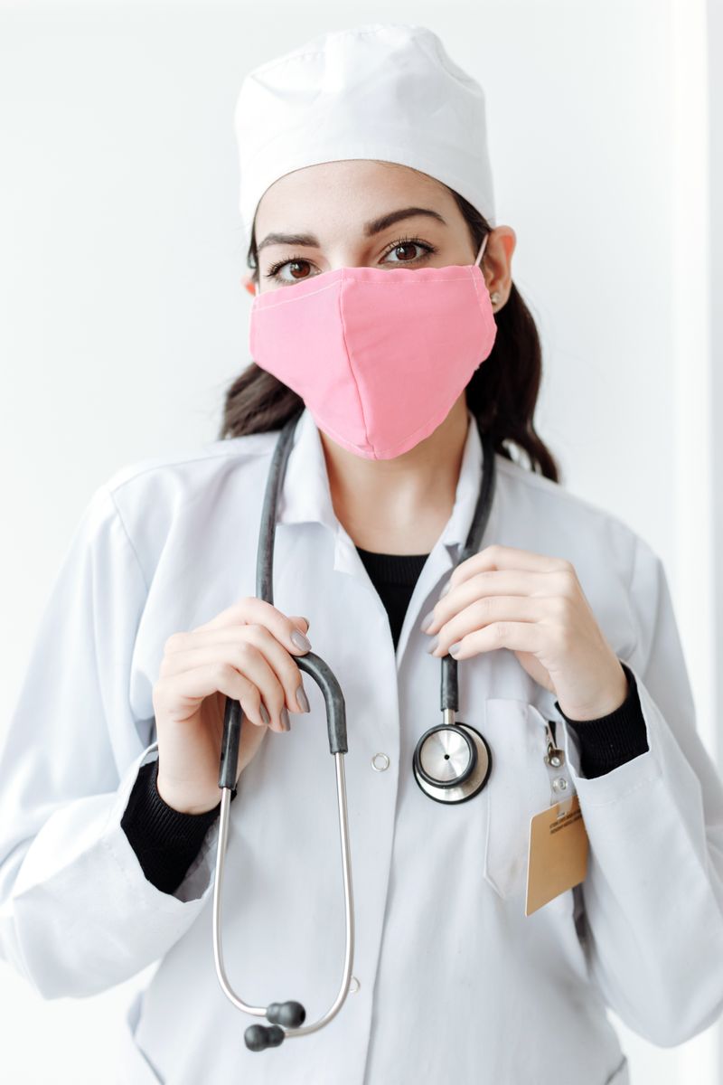 Profesional de la salud con tapabocas rosado (modelo de banco de imágenes)